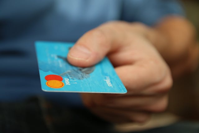 a hand presenting a blue credit card